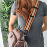 model wearing webster orange black taupe stripe leather bag strap across body attached to greta mink cross body bag