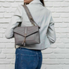 harry warm grey leather crossbody bag worn on shoulder with matching gretchen studded leather strap