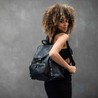 model wearing amber black leather everyday backpack on back ready to take on the day