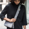 model wearing webster black white zebra leather bag strap across body attached to dark grey milly travel purse