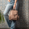 Model holding Amber midi warm taupe leather women's travel bag in hand using sturdy grab and go handle
